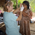 Doctor in village applying ointment to child's eyes